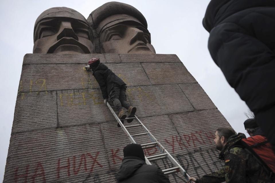 People paint on the KGB officers monument in Kiev, Ukraine, Sunday, Feb. 23, 2014. A top Ukrainian opposition figure assumed presidential powers Sunday, plunging Ukraine into new uncertainty after a deadly political standoff and boosting long-jailed Yulia Tymoshenko's chances at a return to power. The whereabouts and legitimacy of President Viktor Yanukovych are unclear after he left the capital for his support base in eastern Ukraine.(AP Photo/Andrew Lubimov)