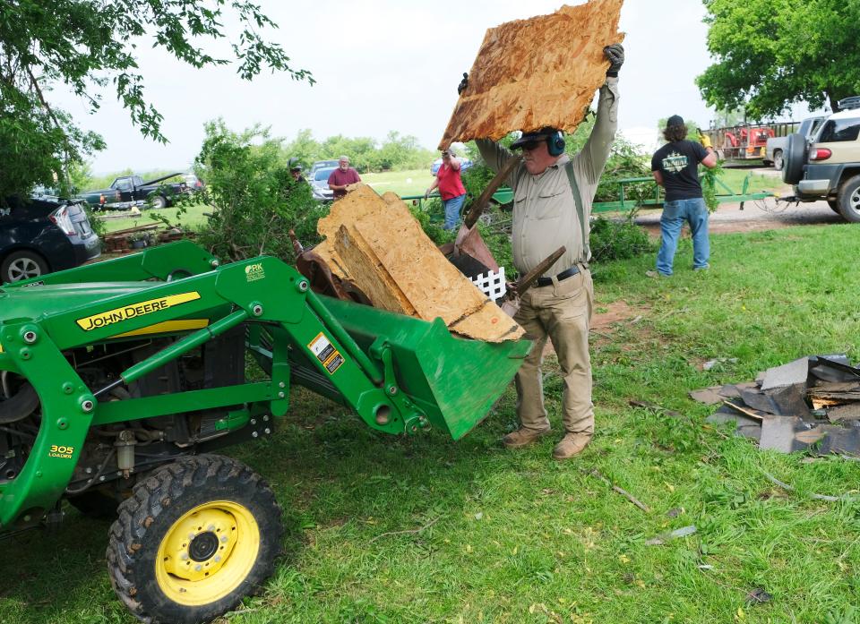 Cole homeowner David Knight loads debris into the bucket of a tractor Friday as he cleans up after a Thursday tornado.