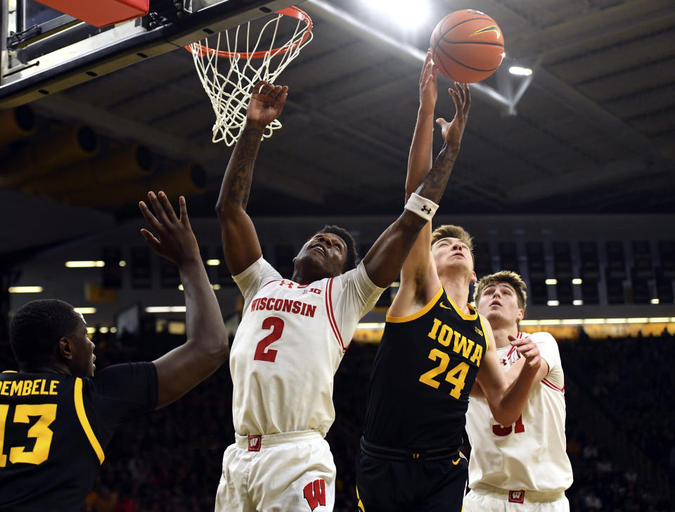 Wisconsin guard AJ Storr (2) and Iowa forward Pryce Sandfort (24) reach for a rebound during the first half of an NCAA college basketball game, Saturday, Feb. 17, 2024, in Iowa City, Iowa. (AP Photo/Cliff Jette)