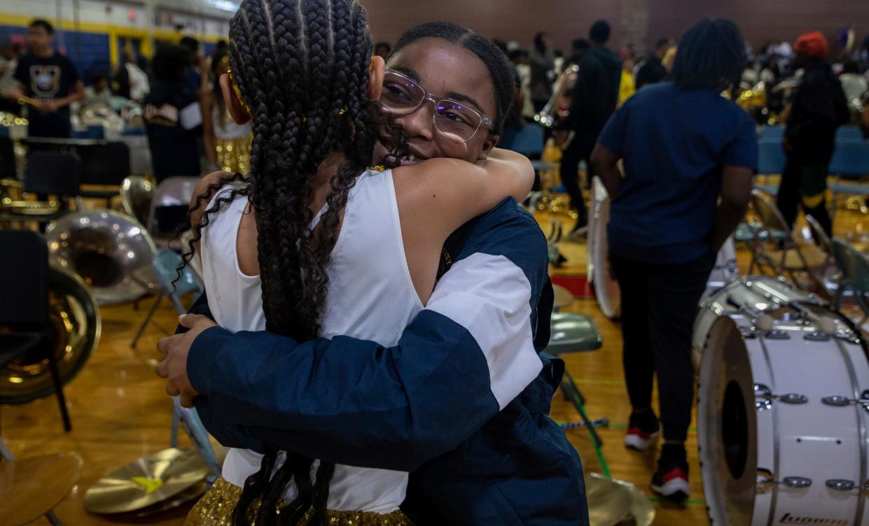 Makaiah Robinson, a Levey Middle School marching band member, hugs a friend during the 8th annual Harvest Festival inside the University High School Academy's gymnasium in Detroit on Wednesday, Nov. 22, 2023.