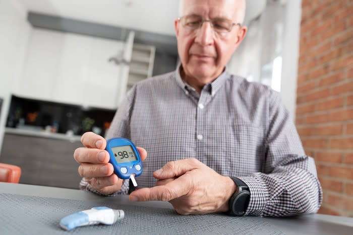 A senior man using a glucometer to check his blood sugar levels.