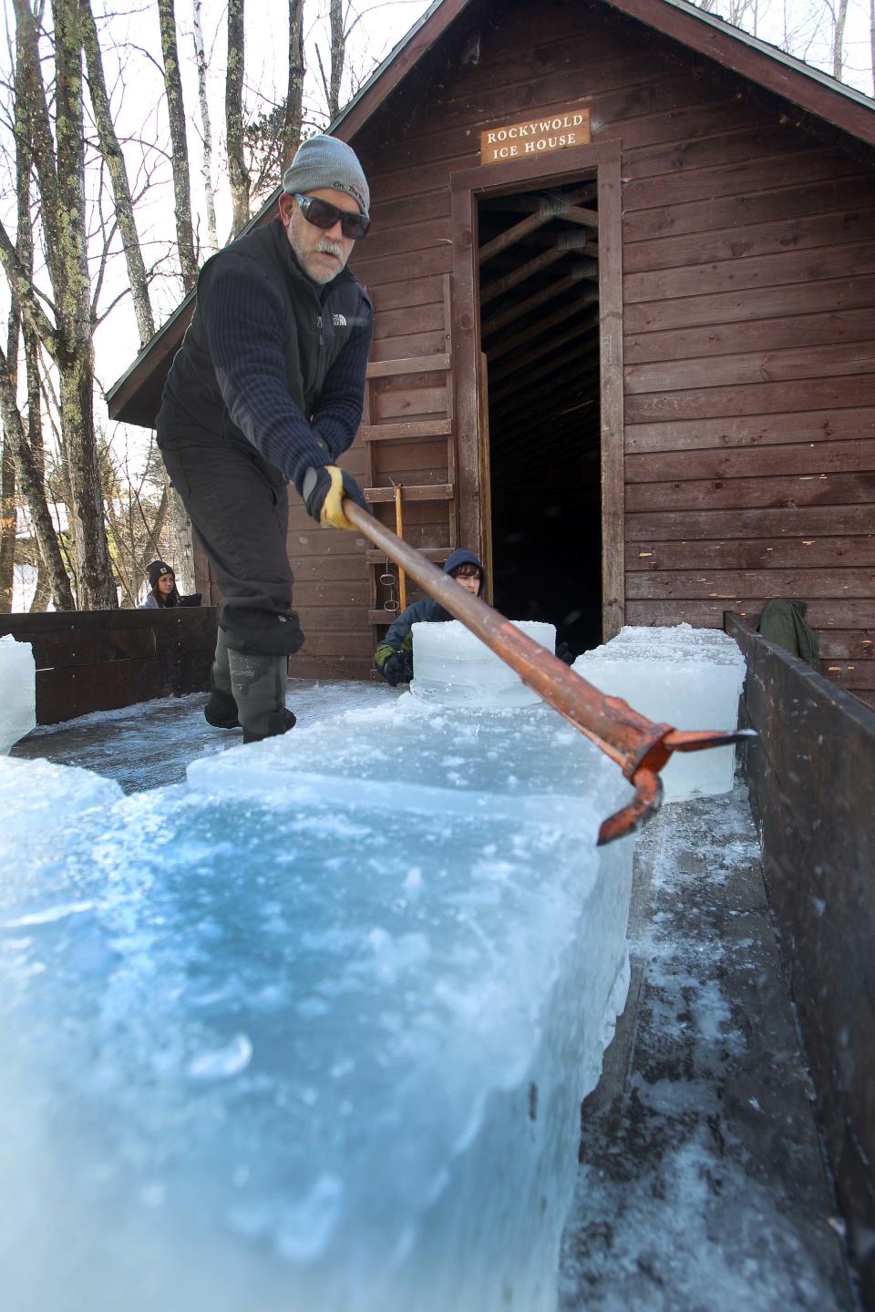 Art Howe guides blocks of ice from the back of his truck Thursday Jan. 9, 2014 to be stored in the in the ice house at the Rockywold-Deephaven Camp in Holderness, N.H. For mare than a century ice has been taken from Squam Lake and stored in the ice house and used for summer residents at the camp. (AP Photo/Jim Cole)