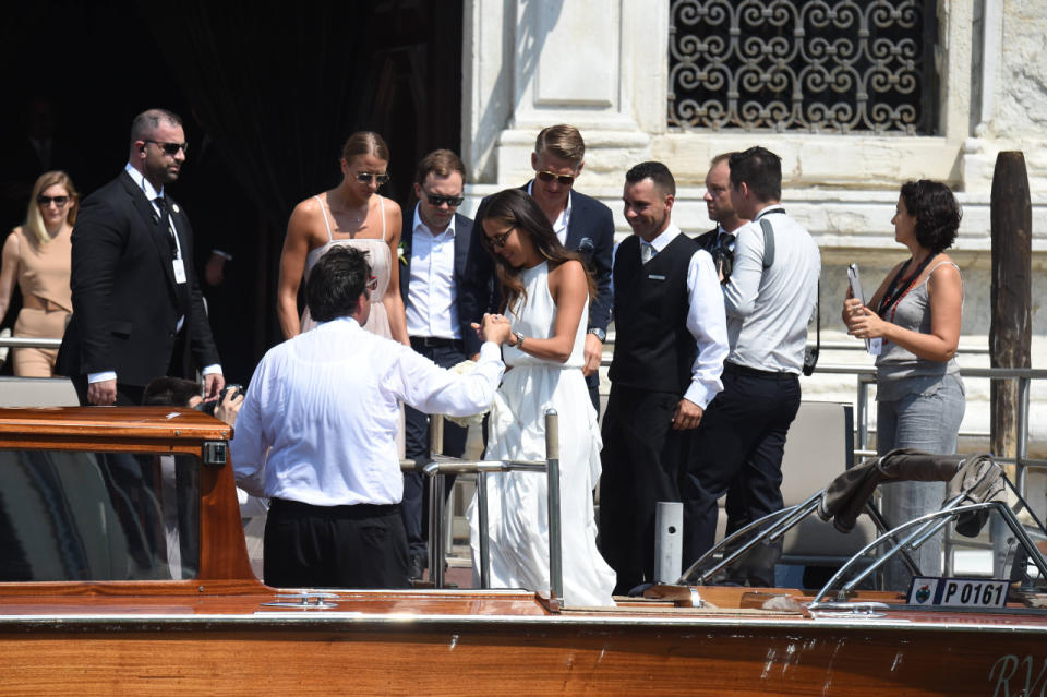 Ana zeigt sich in einem eleganten weißen, schulterfreien Kleid, das in der Taille durch ein schmales Band gerafft ist. In der Hand hält sie einen Strauß weißer Rosen. (Bild: WENN)