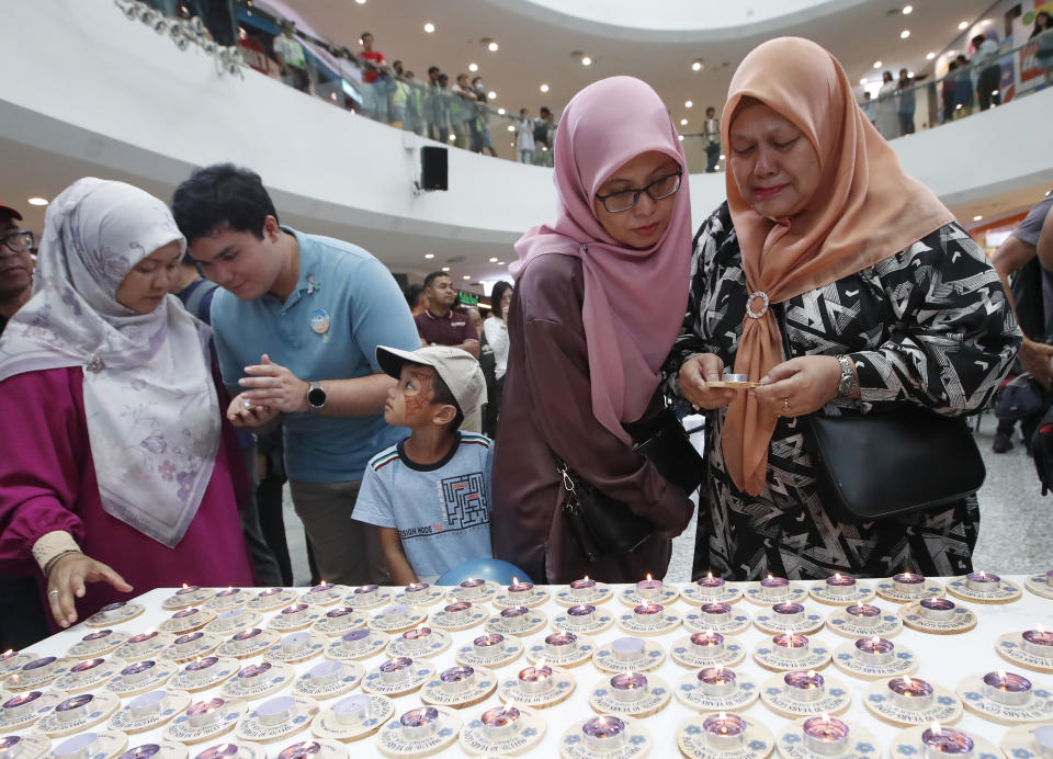Family members and relatives of passengers on board of the missing Malaysia Airlines Flight 370 look at the candles during the tenth annual remembrance event at a shopping mall, in Subang Jaya, on the outskirts of Kuala Lumpur, Malaysia, Sunday, March 3, 2024. Ten years ago, a Malaysia Airlines Flight 370, had disappeared March 8, 2014 while en route from Kuala Lumpur to Beijing with over 200 people on board. (AP Photo/FL Wong)