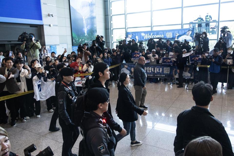 Shohei Ohtani walks past fans with his entourage.