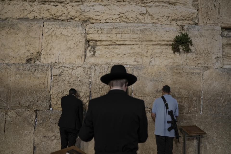 Ultra-Orthodox Jewish men and an off-duty member of Israeli security forces pray at the Western Wall, the holiest site where Jews pray, in Jerusalem's Old City, Monday, Nov. 6, 2023. (AP Photo/Leo Correa)