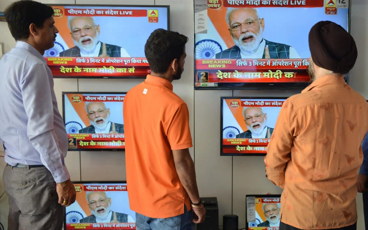 Indian men watch the live broadcast of Indian Prime Minister Narendra Modi's address to the nation  - AFP