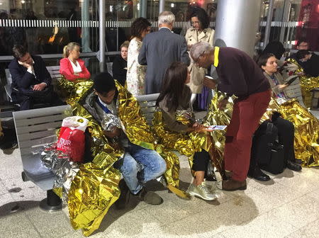 Passengers wrapped in thermal foil blankets given out by emergency services after their Eurostar train was stranded at Calais Station, after intruders were seen near the Eurotunnel, in Calais, France September 2, 2015. REUTERS/John Pullman