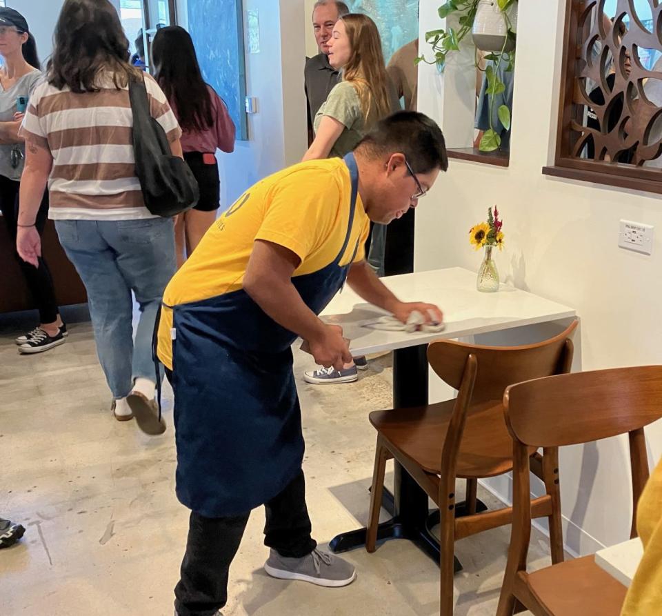 Raymond Tetschner, a Happy Brew barista with Intellectual and Developmental Differences (IDD), cleans a table at the newly opened Happy Brew coffee house.