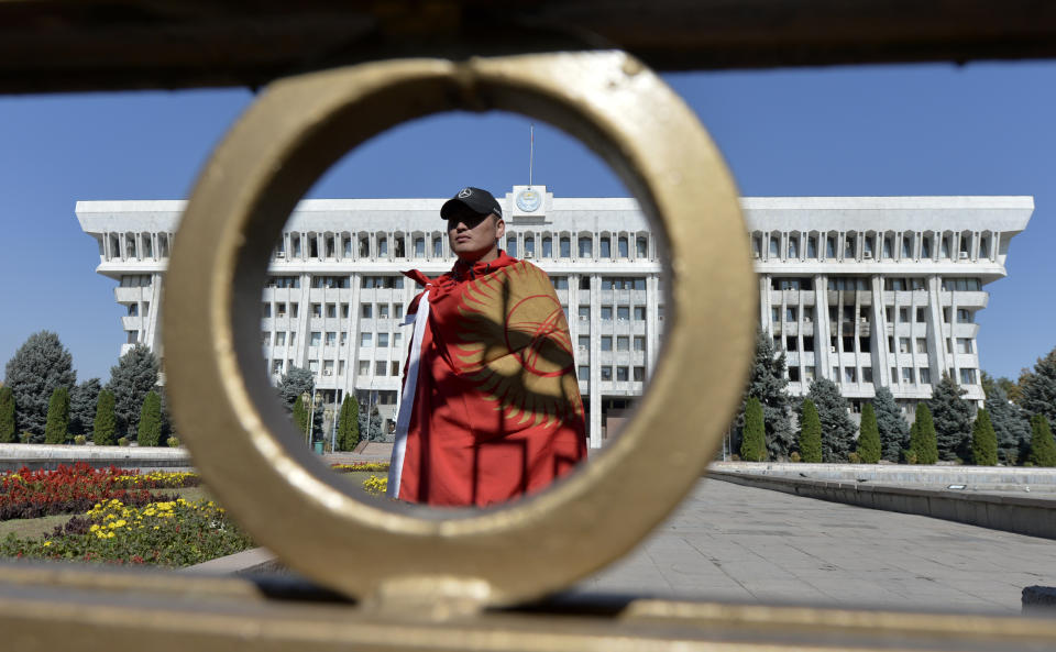 An activist stands in front of the Kyrgyz government headquarters on the central square in Bishkek, Kyrgyzstan, Wednesday, Oct. 7, 2020. Officials in Kyrgyzstan have nullified the results of a weekend parliamentary election after mass protests erupted in the capital of Bishkek and other cities, with opposition supporters seizing government buildings and demanding a new vote. (AP Photo/Vladimir Voronin)