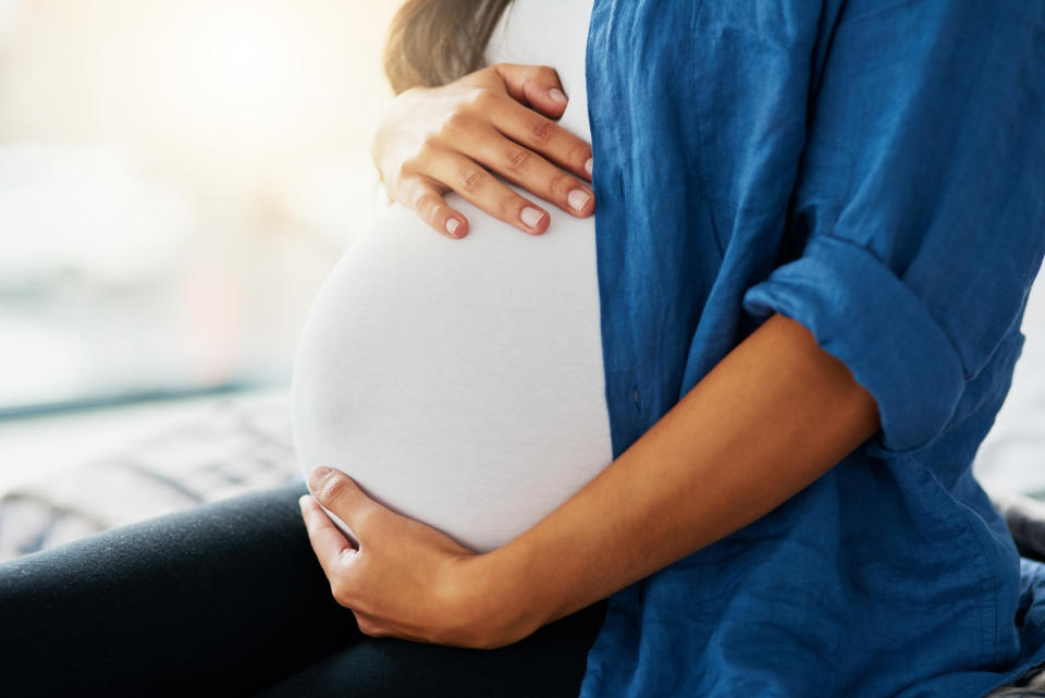 Close-up of a pregnant person holding their stomach