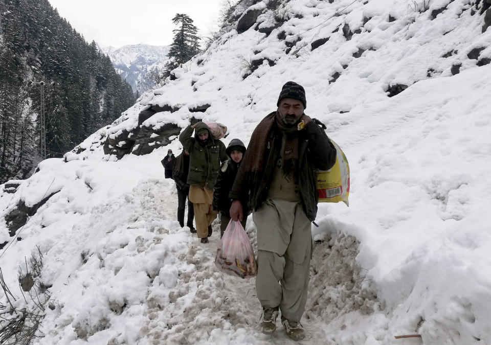 Residentes de Cachemira caminan por un camino cubierto de nieve después de una fuerte nevada en el valle Neelum, en la Cachemira administrada por Pakistán, el miércoles 15 de enero de 2020. (AP Foto/Abdul Razaq)