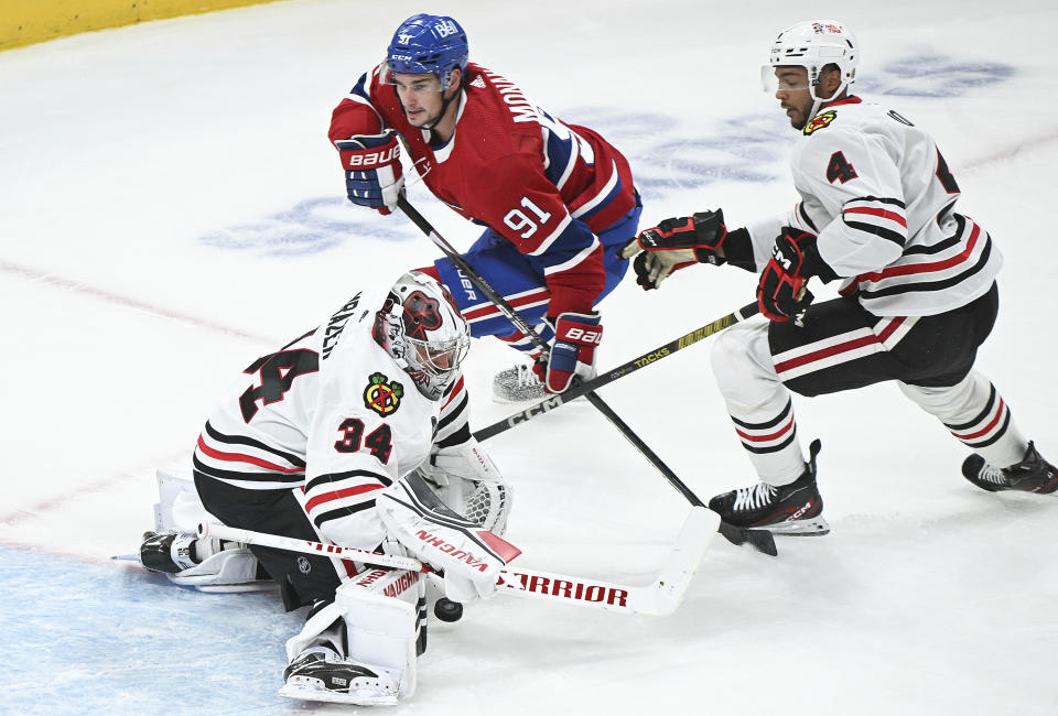 Montreal Canadiens' Sean Monahan (91) moves in on Chicago Blackhawks goaltender Petr Mrazek as Blackhawks' Seth Jones (4) defends during the first period of an NHL hockey game in Montreal, Saturday, Oct. 14, 2023. (Graham Hughes/The Canadian Press via AP)