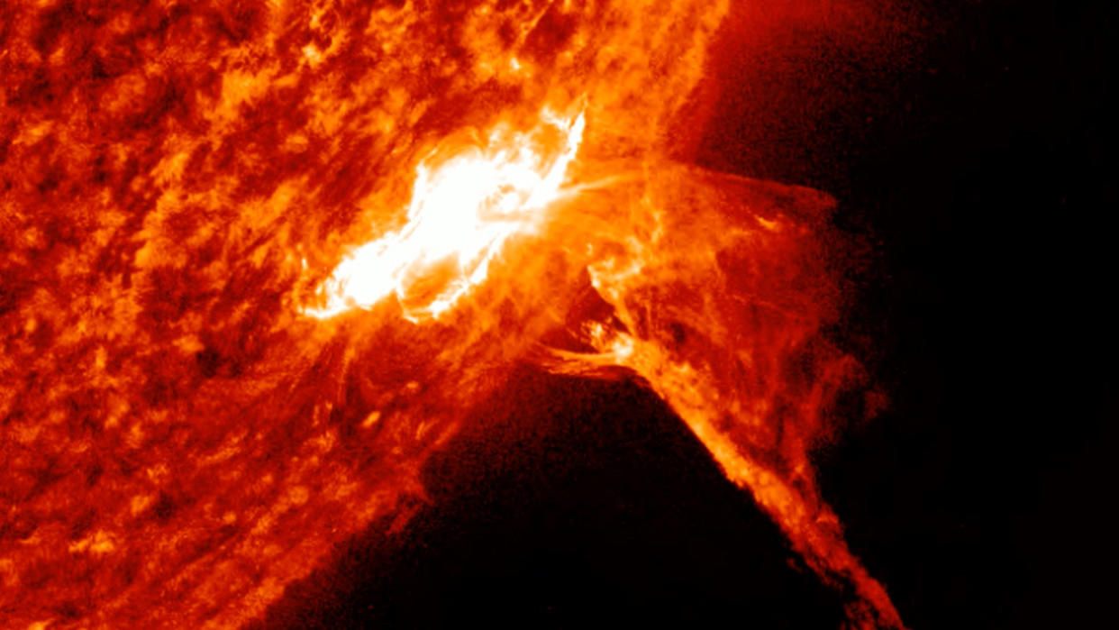  The solar flare appears as a large fiery filament hurled out from the sun. . 