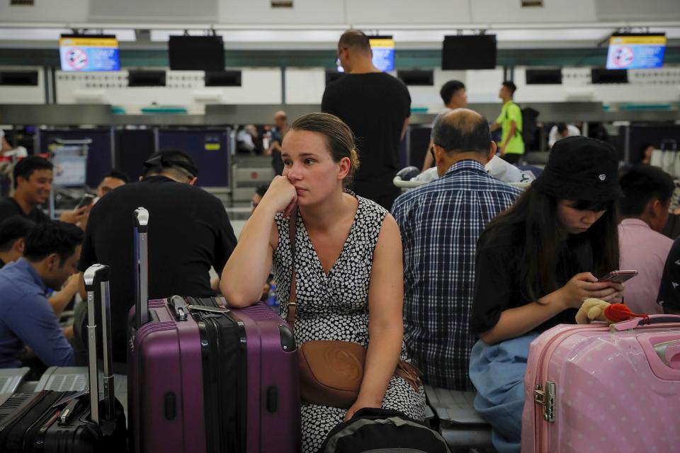 Australian Penny Tilley, center, reacts next to stranded travelers at the closed check-in counters at the Hong Kong International Airport.