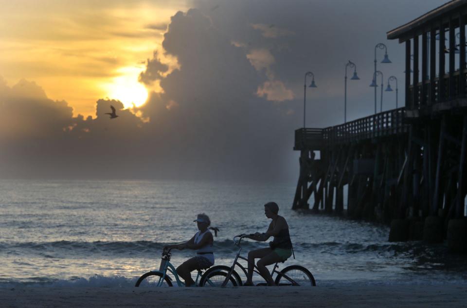 Bicyclists ride past the Daytona Beach Pier as the sun rises in Daytona Beach. The city is ranked among the Top 10 Beach Towns to Retire in the U.S. by U.S. News & World Report.