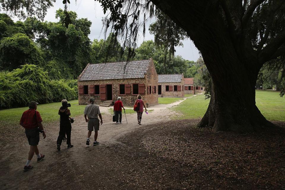 Tourists walk toward the former quarters of people enslaved at Boone Hall Plantation in Mount Pleasant, South Carolina.