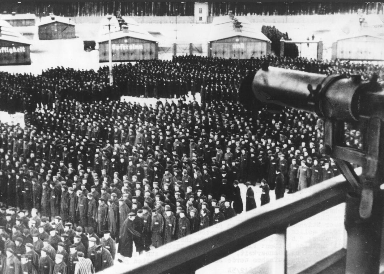 FILE - This undated file photo shows a roll call, in the early morning or late evening hours, on the roll call square in front of the camp gate of the Nazi concentration camp Sachsenhausen in Oranienburg on the outskirts of Berlin, Germany. In the foreground on the tower a machine gun pointed at the prisoners. A 101-year-old man has been convicted in Germany of 3,518 counts of accessory to murder for serving at the Nazis' Sachsenhausen concentration camp during World War II. The Neuruppin Regional Court sentenced him to five years in prison on Tuesday, June 28, 2022. (AP Photo, file)