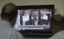 Egyptians watch TV showing the trial of ousted Egyptian president Mohamed Mursi, in Cairo November 4, 2013. Mursi struck a defiant tone on the first day of his trial on Monday, chanting 'Down with military rule', and calling himself the country's only 'legitimate' president. Mursi, an Islamist who was toppled by the army in July after mass protests against him, appeared angry and interrupted the session repeatedly, prompting a judge to adjourn the case. REUTERS/Mohamed Abd El Ghany (EGYPT - Tags: POLITICS CRIME LAW TPX IMAGES OF THE DAY)