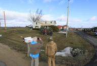 Passersby capture photos of a home and barn which was damaged in a previous day's tornado in Porter, Wis., Friday, Feb. 9, 2024. The first tornado ever recorded in Wisconsin in the usually frigid month of February came on a day that broke records for warmth, the type of severe weather normally seen in the late spring and summer.(John Hart/Wisconsin State Journal via AP)