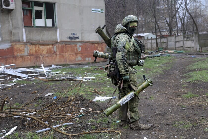 FILE - An armed serviceman of Donetsk People's Republic militia walks past a building damaged during fighting in Mariupol, on the territory which is now under the Government of the Donetsk People's Republic control, eastern in Mariupol, Ukraine, Wednesday, April 13, 2022. (AP Photo/Alexei Alexandrov, File)