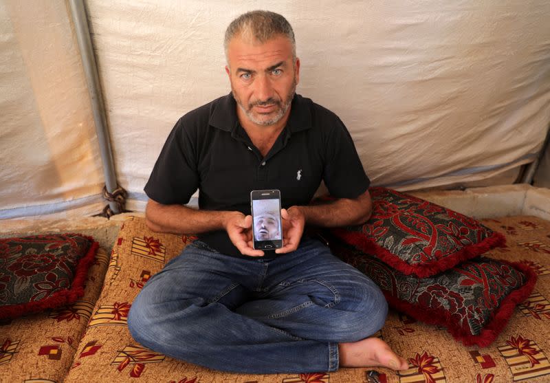 Issam Faysal Youssef, 40, displays a picture of his deceased cousin in Idlib