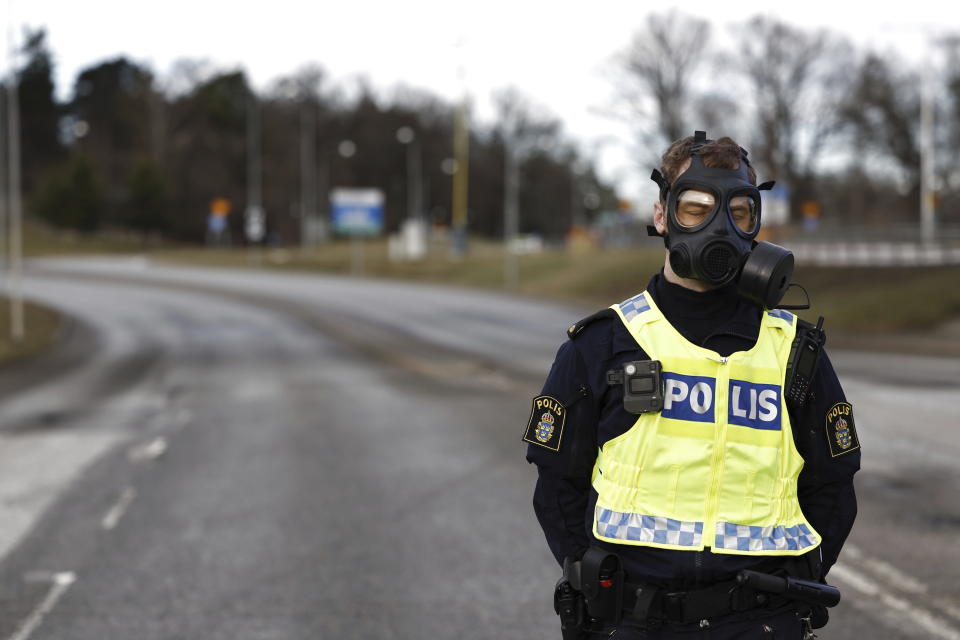 A police officer with a gas mask stands guard near the Security Police's headquarters in Solna, north of Stockholm, Sweden, Friday Feb. 23, 2024. A suspected gas leak at the headquarters of Sweden’s security agency on Friday forced the authorities to evacuate some 500 people from the facility, Swedish broadcaster TV4 said. (Fredrik Persson/TT News Agency via AP)