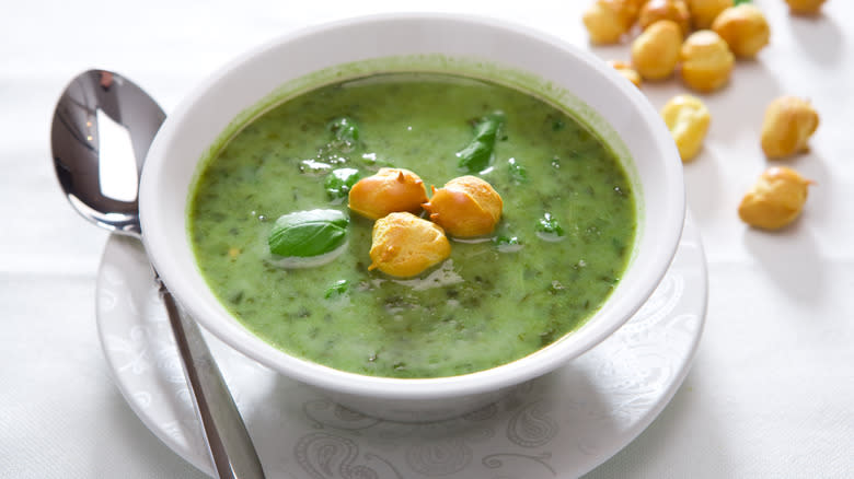 Green soup in white cup with croutons