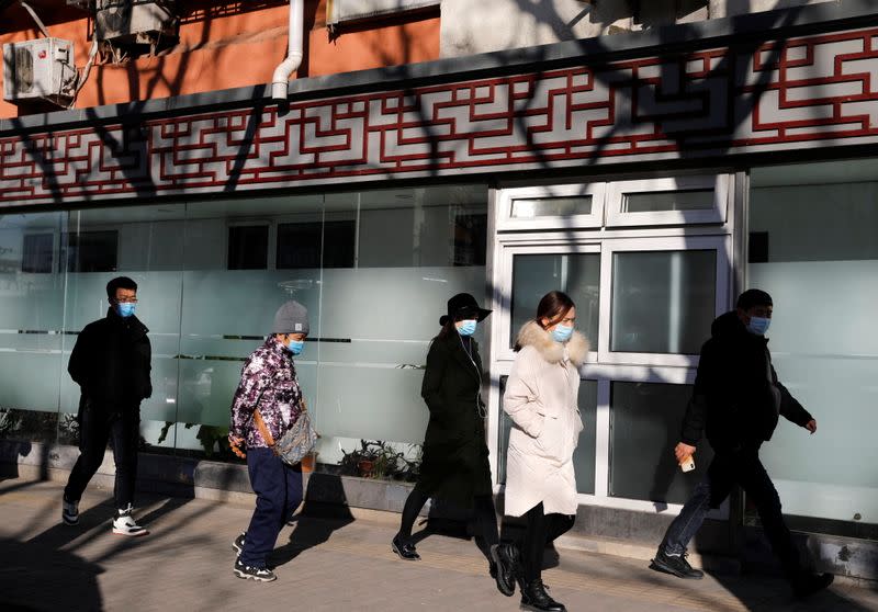 People wearing masks walk in a street in Beijing's CBD during morning rush hour