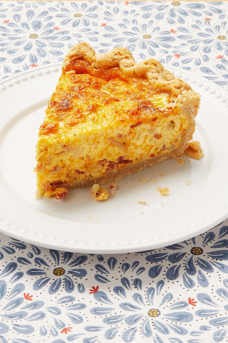 egg quiche on white plate with blue floral cloth