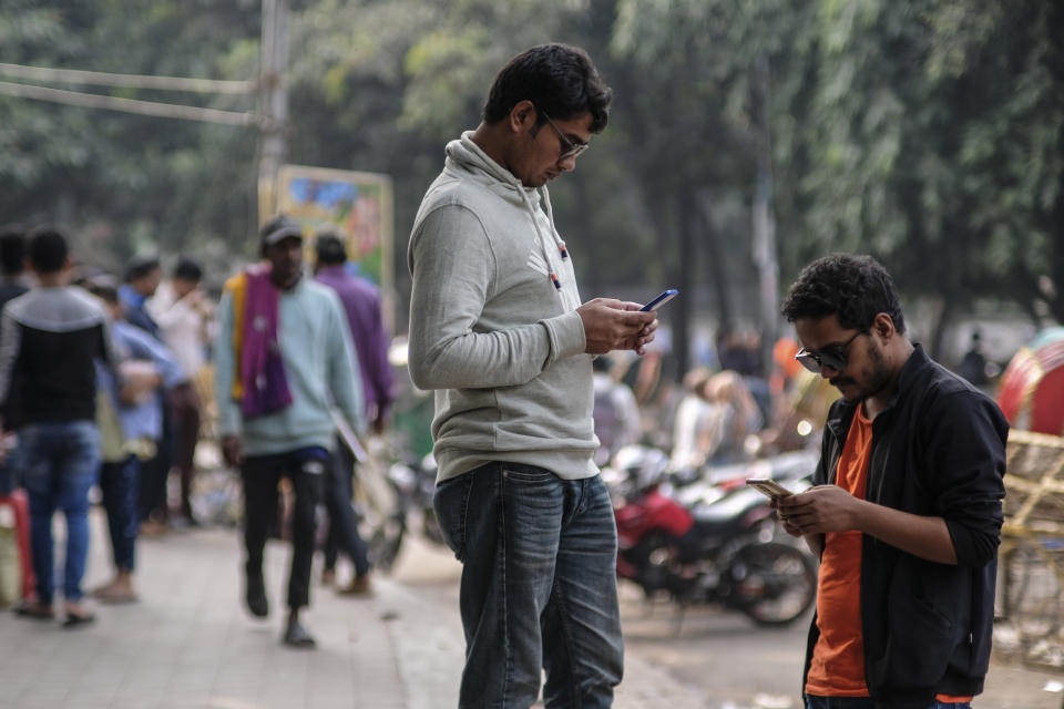 People use their mobile phones at Dhaka University area, Bangladesh, Dec.21, 2023. For decades, political battles in Bangladesh have been fought on the streets, often with violence, by parties led by two powerful women. But there are signs of a generational change as the country of 169 million heads into another general election Sunday. (AP Photo/Mahmud Hossain Opu)