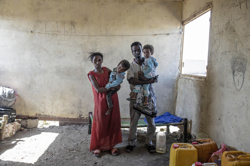Tesfaalem Germay, 34, an ethnic Tigrayan survivor from Mai-Kadra, Ethiopia, poses for a photograph with his wife Bethlehem, 21, and their twin daughters inside a temporary shelter at Village 8, the transit center near the Lugdi border crossing, eastern Sudan, Nov. 22, 2020. Witnesses say hundreds of civilians were slaughtered in Mai-Kadra, but they disagree about who killed whom. "Anyone they found, they would kill," Germay said of Ethiopian federal and Amhara regional forces. Others say it was Tigrayan forces and their allies who were responsible. (AP Photo/Nariman El-Mofty)