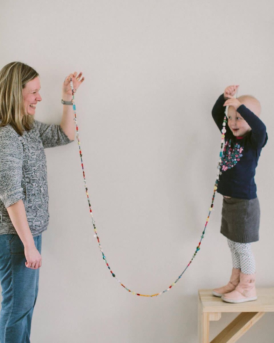 Mum Sarah helps Evie show off her beads showing how many treatments she's had. Photo: Supplied