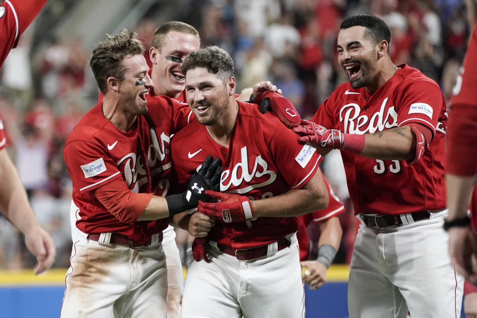 Cincinnati Reds' Hunter Renfroe, center, is congratulated by TJ Friedl, left, after hitting a grounder that scored the winning run during the ninth inning of the team's baseball game against the Chicago Cubs, Saturday, Sept. 2, 2023, in Cincinnati. Friedl scored the winning run. (AP Photo/Joshua A. Bickel)