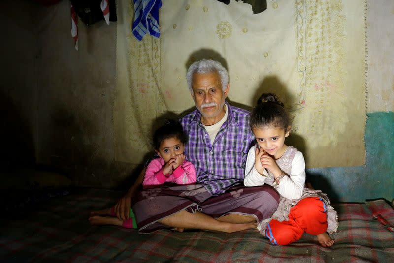 Ahmad Farea sits with his daughters at their house in Sanaa