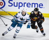 San Jose Sharks forward Fabian Zetterlund, left, and Calgary Flames forward Mikael Backlund chase the puck during the first period of an NHL hockey game in Calgary, Alberta, Saturday, March 25, 2023.(Jeff McIntosh/The Canadian Press via AP)