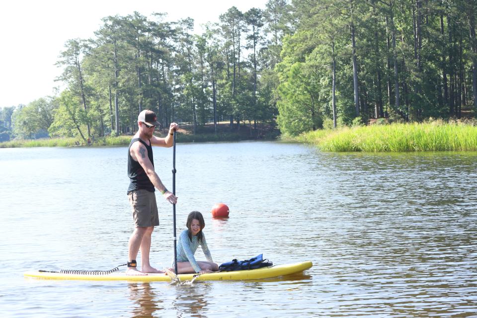 Libby Frederick of Pineville sits on a paddle board while her dad Kyle Frederick paddles around the Little Beach at Indian Creek Recreation Area in Woodworth. The paddle board was provided by River Paddle Rentals located in Alexandria.