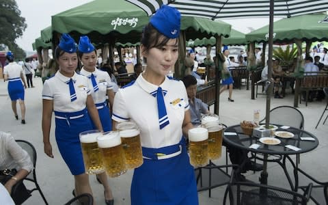 A waitress carrying jugs of beer to guests before the opening of the Pyongyang Taedonggang Beer Festival on the banks of the Taedong - Credit: KIM WON-JIN/ AFP