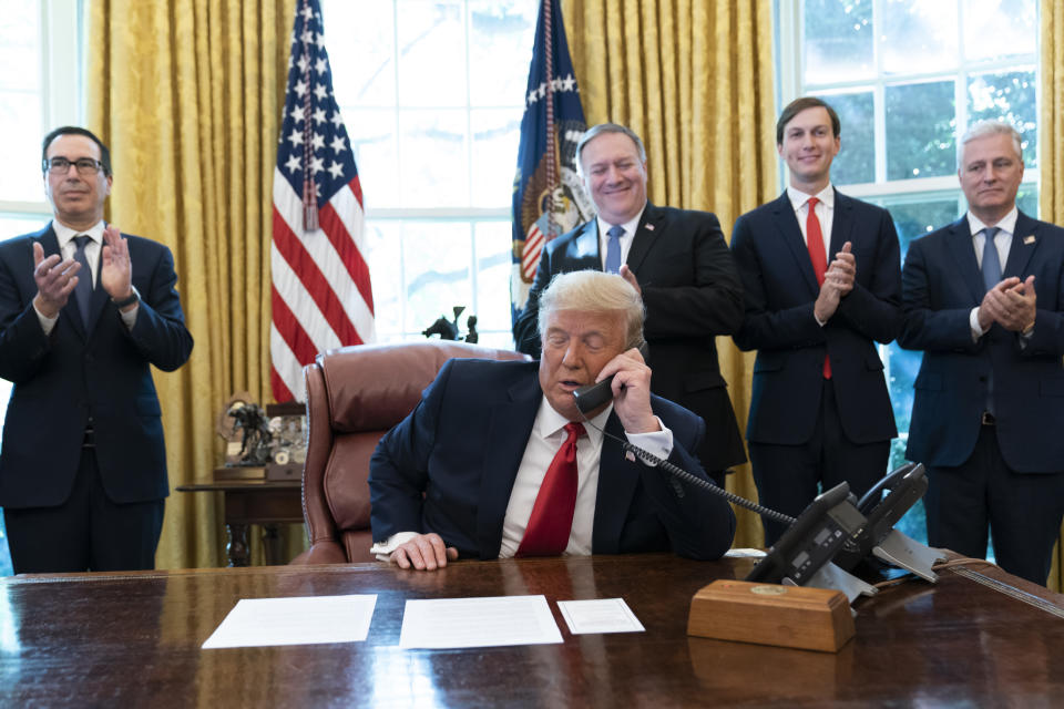 FILE - In this Oct. 23, 2020 file photo, President Donald Trump talks on a phone call with the leaders of Sudan and Israel, as Treasury Secretary Steven Mnuchin, left, Secretary of State Mike Pompeo, White House senior adviser Jared Kushner, and National Security Adviser Robert O'Brien, applaud in the Oval Office of the White House, in Washington. The U.S. Embassy in Khartoum said the administration removed Sudan from the U.S. list of state sponsors of terrorism, a move that could help the African country get international loans to revive its battered economy and end its pariah status. The embassy said in a Facebook post that the removal of Sudan from the list is effective as of Monday, Dec. 14, 2020. Delisting Sudan from the state sponsors blacklist is a key incentive for the Sudanese government to normalize relations with Israel. (AP Photo/Alex Brandon, File)