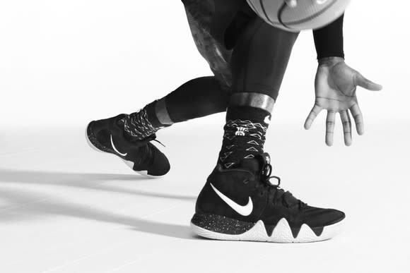 A pair of Nike basketball shoes shown with a pair of hands dribbling a basketball.