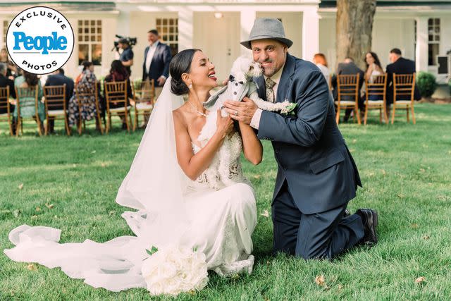 <p>Lola Grace Photography</p> Jasmine Pineda and Gino Palazzolo pose with a tuxedo-clad dog at their wedding