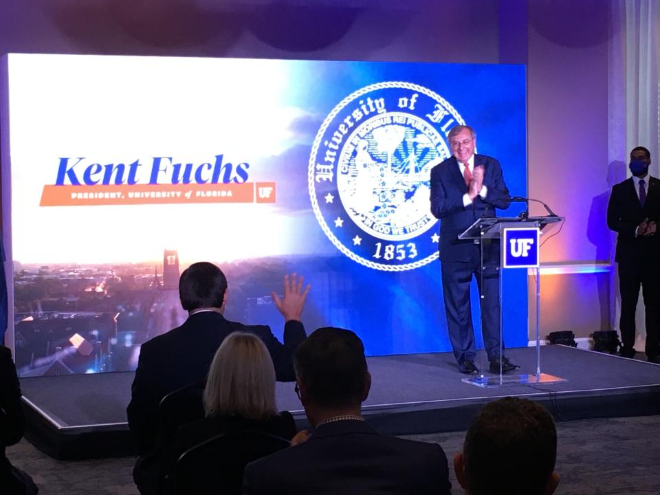 UF President Kent Fuchs stands at the lectern to announce a top-five ranking by U.S. News & World Report, and acknowledges the visit Gov. Ron DeSantis, with his hand raised to wave back.
