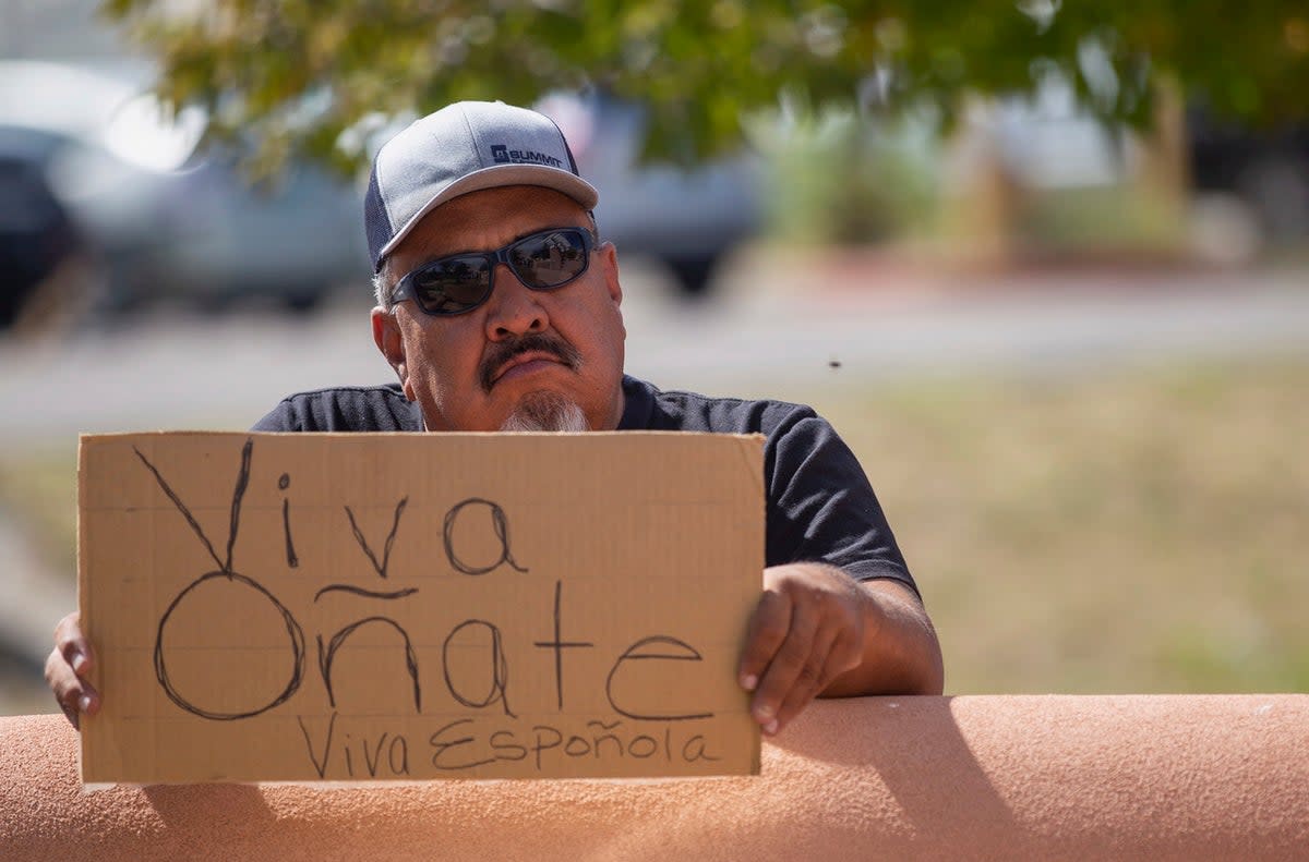 An onlooker holds a “Viva Oñate” sign while demonstrators gather in front of the Rio Arriba County Complex to protest the placing of a statue of a Spanish conquistador  (AP)