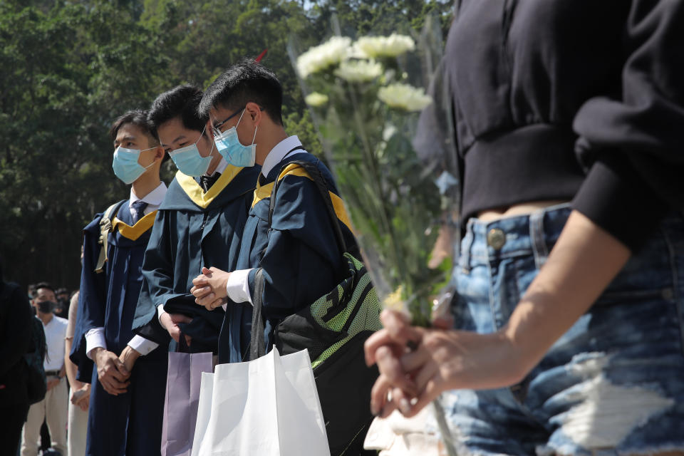 Graduate students pause at a makeshift memorial for Chow Tsz-Lok after a graduation ceremony was disrupted at the University of Science and Technology in Hong Kong on Friday, Nov. 8, 2019. Chow, a student from the University who fell off a parking garage after police fired tear gas during clashes with anti-government protesters died Friday, in a rare fatality after five months of unrest that intensified anger in the semi-autonomous Chinese territory. (AP Photo/Kin Cheung)