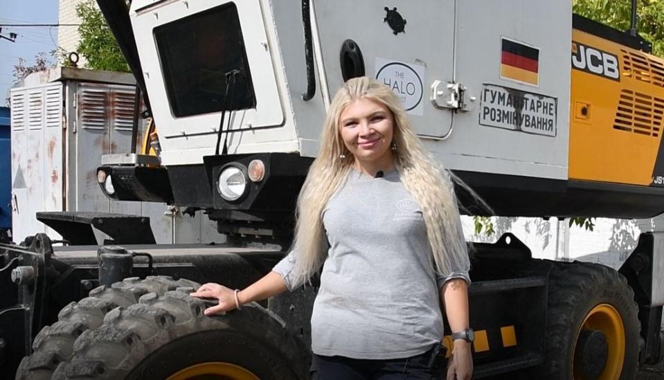 Ilona, a demining worker with The HALO Trust, is seen in a file photo standing next to the kind of armored excavator she operates in her work to find and safely remove landmines in Ukraine.  / Credit: Ilona/HALO Trust