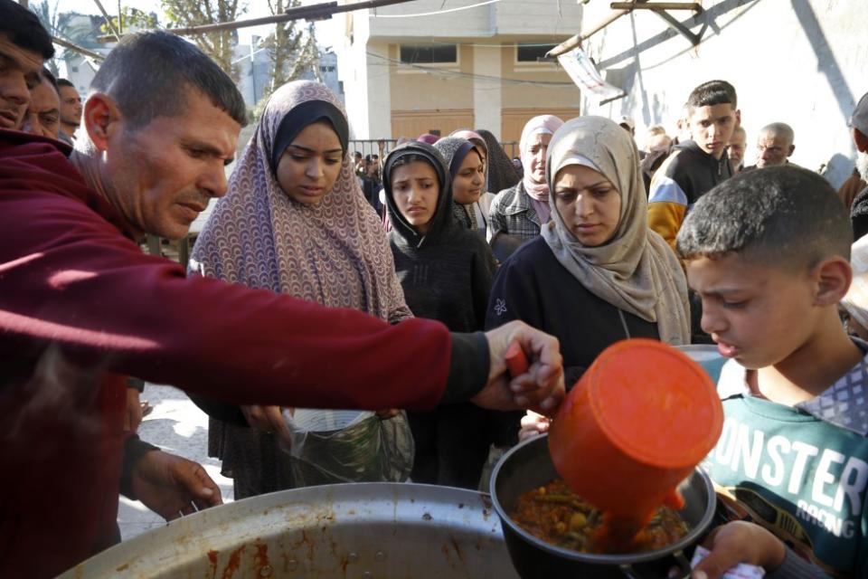 Palestinians queue to receive food from aid organizations