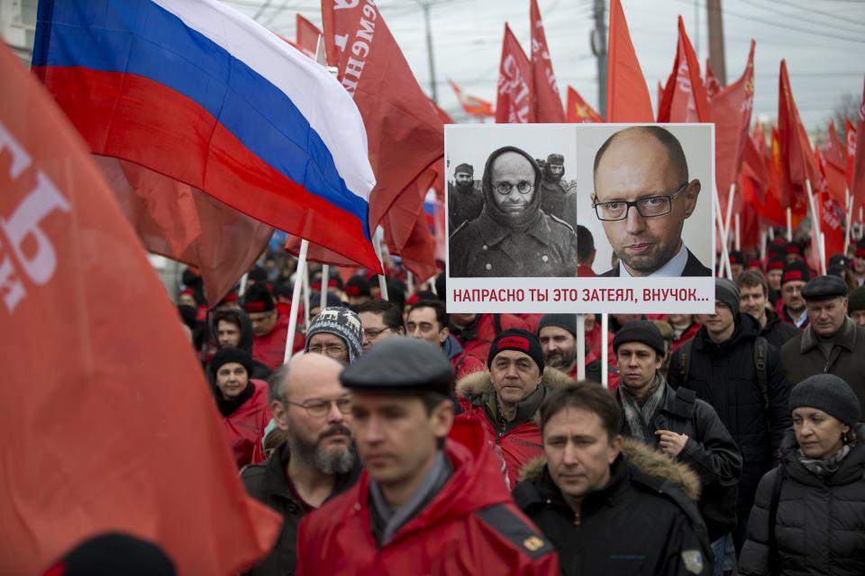 Demonstrators march in support of Kremlin-backed plans for the Ukrainian province of Crimea to break away and merge with Russia, in Moscow, Saturday, March 15, 2014. Large rival marches have taken place in Moscow over Kremlin-backed plans for Ukraine’s province of Crimea to break away and merge with Russia. A poster depicts photos of WWII German prisoner of war and Ukrainian prime minister Arseniy atsenyuk,and says "Your project is doomed, grandson…" (AP Photo/Alexander Zemlianichenko)