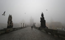 A man walks across the medieval Charles Bridge in Prague, Czech Republic, Wednesday, Feb. 24, 2021. The Czech government has decided to further tighten restrictive measures amid a surge of a highly contagious coronavirus variant in one of the hardest-hit European Union's nations. At the same time, the worsening situation has forced the Cabinet to abandon for now its plans to reopen all stores. (AP Photo/Petr David Josek)