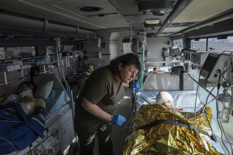 An injured Ukrainian soldier speaks to a volunteer from the Hospitallers paramedic organisation inside a special medical bus during the evacuation in Donetsk region, Ukraine, Wednesday, March 22, 2023. (AP Photo/Evgeniy Maloletka)