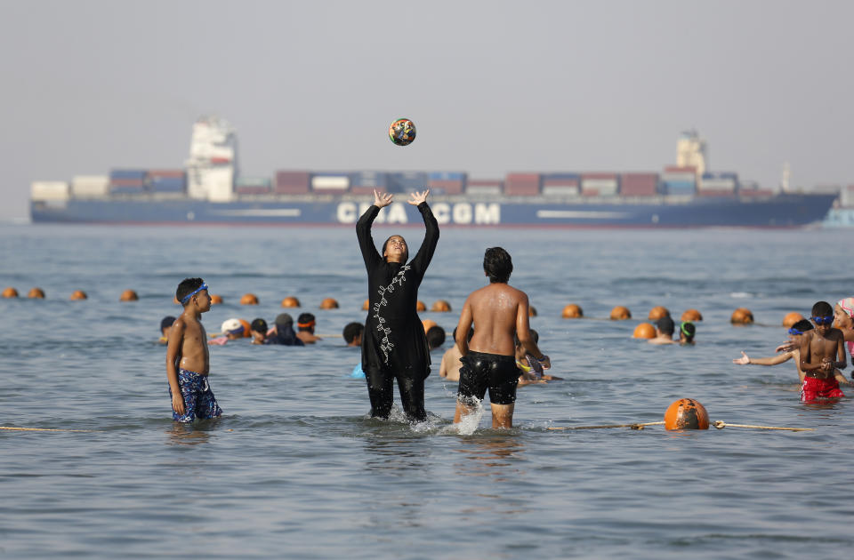 FILE - In this July 19, 2018 file photo, holidaymakers play in the Red Sea, at El Sokhna beach in Suez, Egypt, Egypt. The burkini, a swimsuit worn by conservative Muslims to cover the entire body, is scorned in many upper class Egyptian circles where it and the headscarf is seen as lower class. Women who wear the burkini or headscarves can face discrimination in upper-class beach resorts or in bars or clubs, though across Egypt the majority of women wear conservative dress. (AP Photo/Amr Nabil, File)